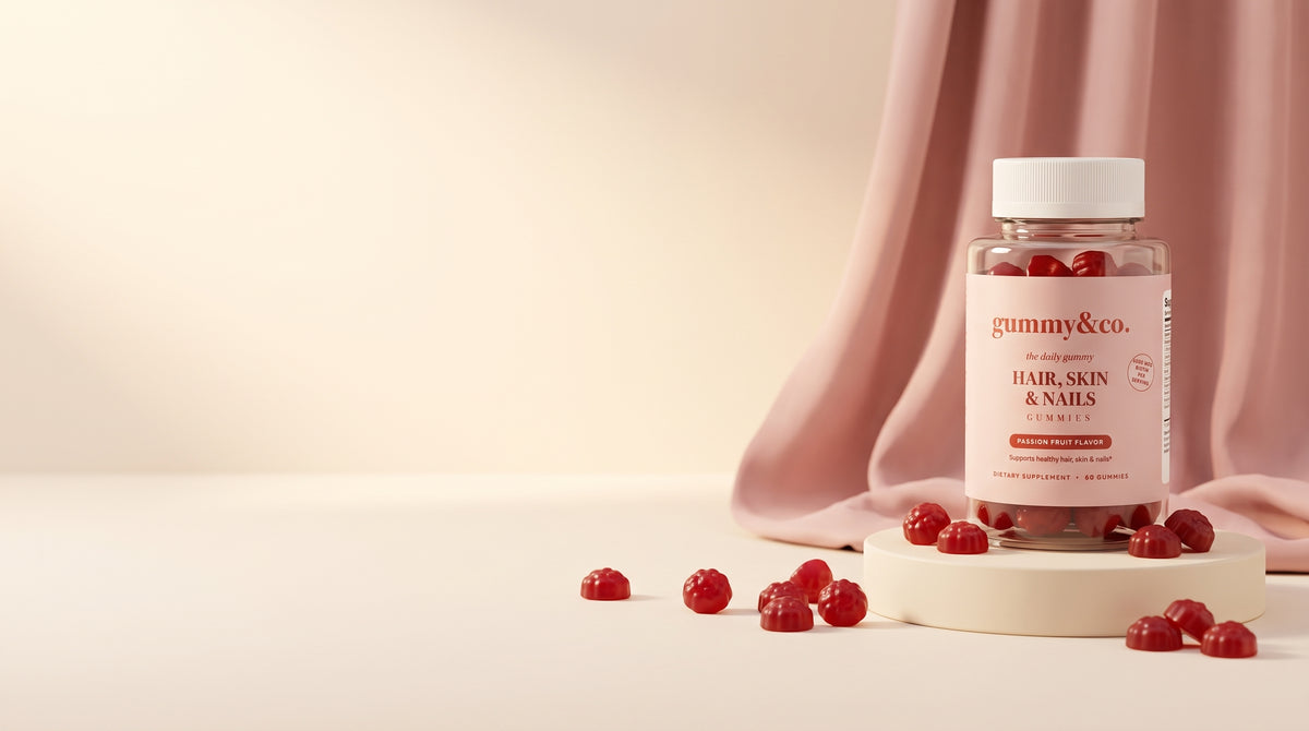 Gummy & Co. Hair, Skin & Nails Gummies bottle on a pedestal with scattered passion fruit gummies